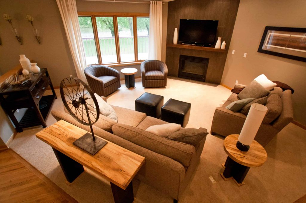 小型现代客厅，灰色墙壁，沙发和扶手椅，小角落壁炉和壁炉上方的电视