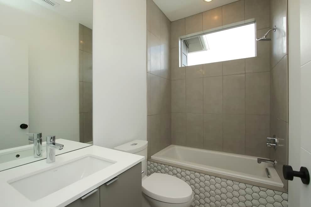 白色的蜂窝瓷砖浴缸，灰色的橱柜，灰色的墙壁