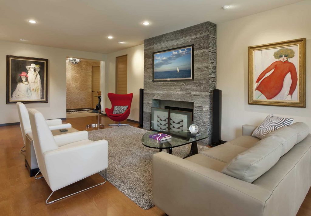 宽敞的客厅，木地板，白色墙壁和扶手椅，灰色沙发，小斑马大理石壁炉和壁炉上方的电视