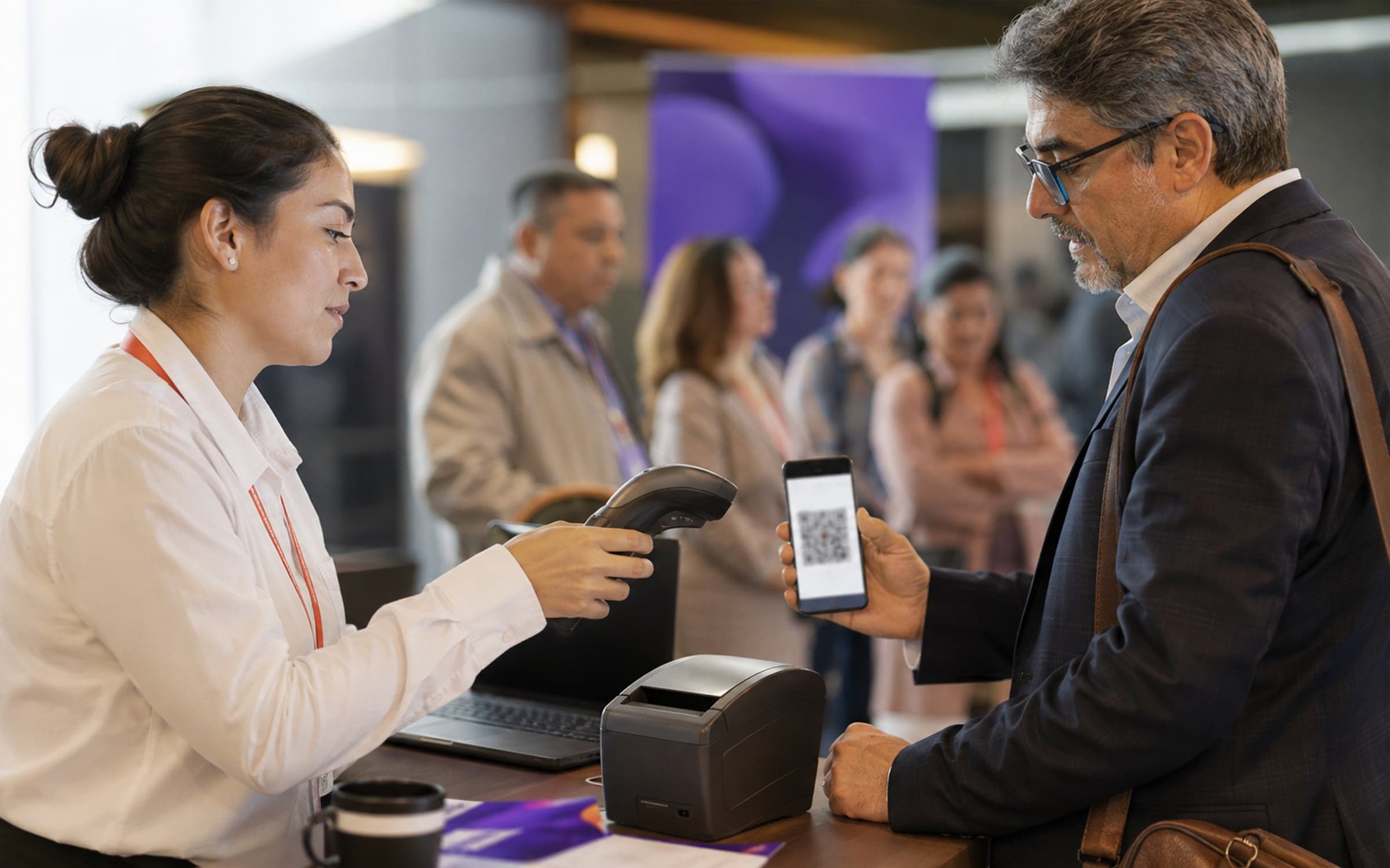 Una persona del staff escanea la credencial QR en el teléfono de un médico en la mesa de acreditación